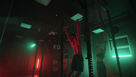 male-and-female-athletes-are-doing-pull-up-on-bar-in-fitness-center-training-hard